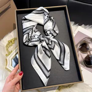 Detailed view of black and white geometric silk scarf displayed in an elegant gift box