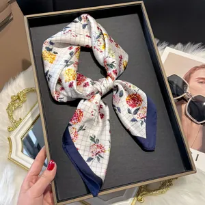 Detailed close-up of floral pattern silk scarf with navy blue border on display tray