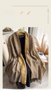 Detailed texture of imitation cashmere shawl with golden paisley pattern and fringe