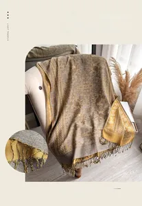 Close-up of golden paisley cashmere-style scarf featuring hand-knotted long tassels