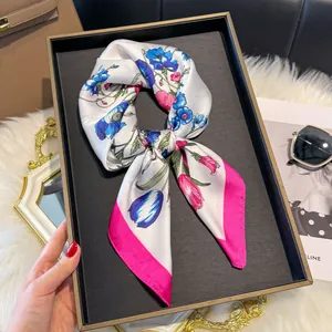 Dettaglio dell'elegante foulard in seta con fiori e bordo rosa su vassoio da esposizione