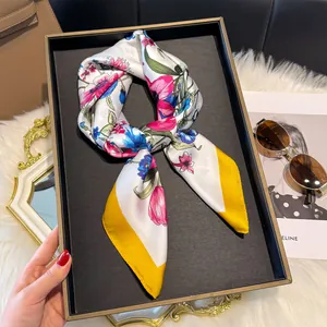 Dettaglio macro del foulard in seta 70cm con fiori rosa e bordo giallo su vassoio
