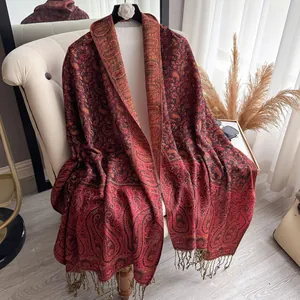 Detail of red paisley jacquard cashmere-feel shawl with elegant fringe and thick texture