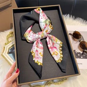 Dettaglio di elegante foulard in seta con gigli e catene d'oro annodato a fiocco