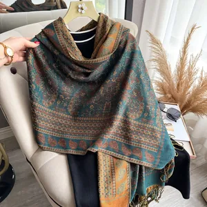 Detail of vintage paisley shawl with dark green and brick red patterns and fringe