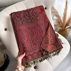 Detailed macro view of vintage dark red paisley jacquard pattern and bronze fringe tassel