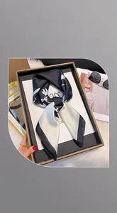 Détail d'un foulard en soie noir et blanc plié dans un coffret cadeau noir de luxe