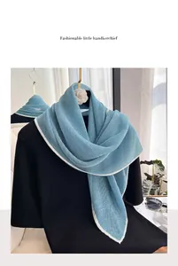 Close-up of light blue pleated neck scarf with white edges and camellia brooch detail