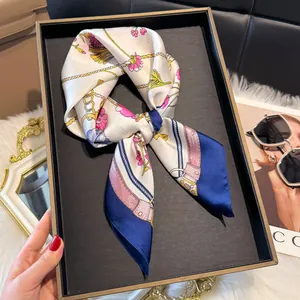 Dettaglio di un elegante foulard in raso con stampa floreale, catene d'oro e bordo blu navy