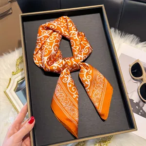 Detail van oranje zijden sjaal met wit paisley patroon op luxe display plateau