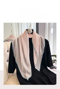 Detail of pink pleated faux silk scarf with blue edges on a black top with camellia hanger