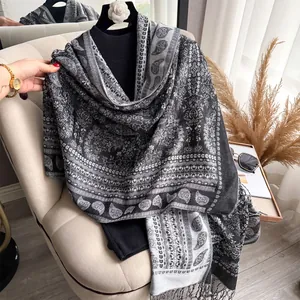 Detail of paisley pattern and soft fringe on a thick black and white pashmina scarf