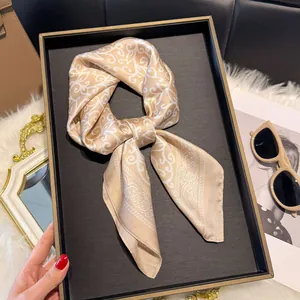 Elegante zijden sjaal in champagne en wit met paisley patroon op een zwart dienblad