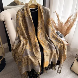 Ginger yellow paisley cashmere-like scarf with fringe on a studio mannequin and chair