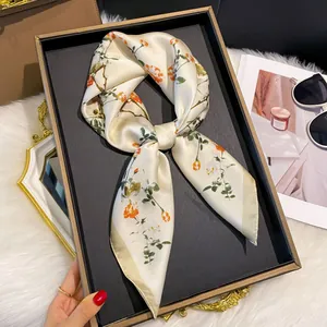 Détail d'un foulard en satin de soie avec motif floral orange et nœud élégant