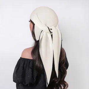 Detailed close-up of white pleated headscarf with contrasting black stitched edges