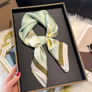 Dettaglio di elegante sciarpa in seta con stampa di gigli e bordo verde scuro sul display