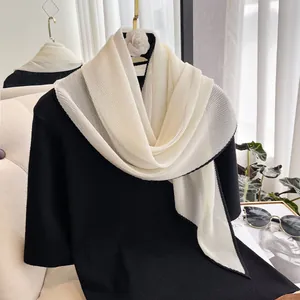 Detailed view of white pleated scarf with black contrast hem on a display stand