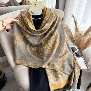 Macro detail of paisley pattern and tassels on a gold-grey cashmere feel shawl scarf