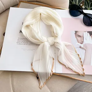 Detail of white pleated faux silk scarf with brown trim on a fashion magazine