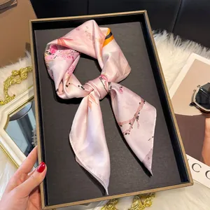 Dettaglio di un foulard in seta rosa con motivo ciliegio su un vassoio decorativo nero