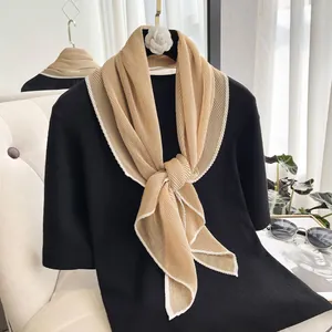 Detail of champagne gold pleated scarf with wavy white hem edge decoration