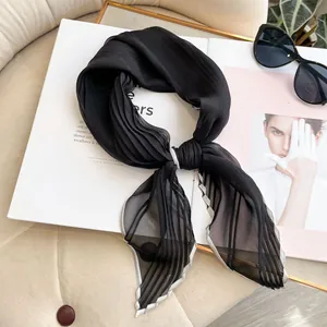 Detail of pleated black silk scarf with silver stitching on fashion magazine background