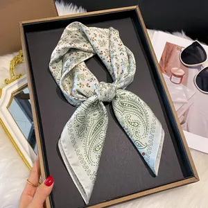 Élégant foulard en soie à motif cachemire et fleurs sur un plateau gris avec accessoires