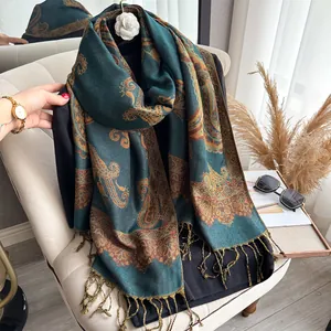 Detail of teal cashmere-feel scarf with golden paisley patterns and fine tassel edges