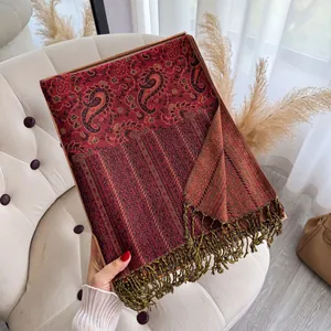 Detail eines burgunderfarbenen Paisley-Schals mit Quasten in einer Geschenkbox