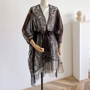 Detail van kanten vest met zwarte strik, wit bloemen haakwerk en franjes aan de zoom