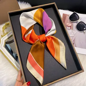 Détail d'un foulard en satin multicolore plié avec élégance dans un coffret cadeau