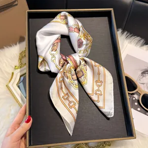 Gedetailleerde close-up van een zijden sjaal met vintage kettingprint op een luxe dienblad