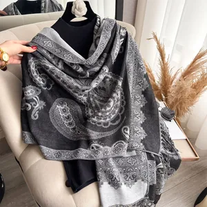 Close-up of black cashmere-like shawl with paisley pattern and tassels on sofa