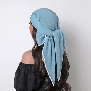 Detail of pleated dusty blue silk scarf featuring a white contrast border and soft drape