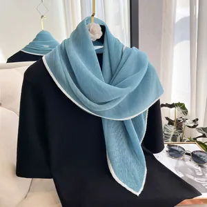 Detail of blue pleated scarf with white edges draped over black t-shirt accessory
