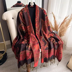 Detail of paisley patterns and fringes on a thick dark brown and red pashmina shawl