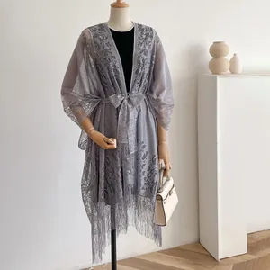 Detail van grijs kanten vest met vintage bloemenpatronen en zoom met lange franjes