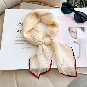 Pleated faux silk scarf in beige with contrast red edges on magazine background