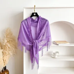 Detail of purple lace shawl with floral patterns and elegant long fringe hanging on a rack