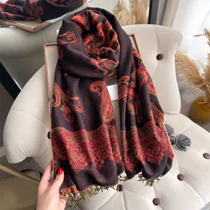 Close-up of dark brown paisley cashmere shawl with fringe trim on an armchair