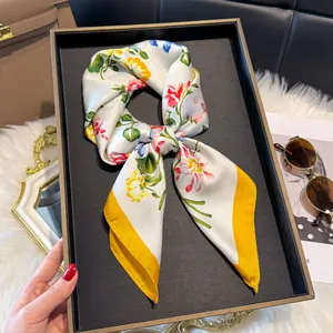 Dettaglio foulard in seta floreale con bordo giallo su un vassoio da esposizione retrò