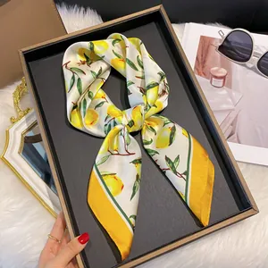 Détail d'un foulard en satin aux imprimés citrons avec bordure jaune élégante
