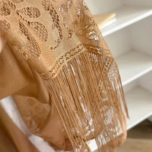 Detailopname van bohemian goudkleurig kanten vest met opengewerkte patronen en franjes