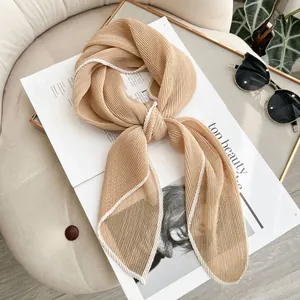 Elegant khaki pleated scarf with contrast wavy trim on a stylish magazine background