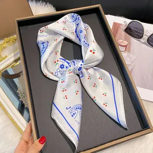 Détail d'un foulard en satin aux motifs cerises et paisley sur un plateau élégant