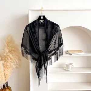 Close-up of black lace triangle shawl with hollow patterns and elegant long fringe