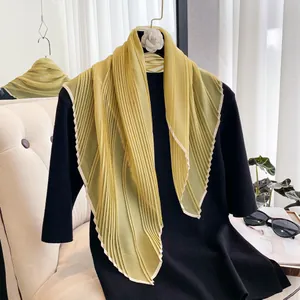 Detail of olive green pleated chiffon scarf with delicate beige piped edge on a hanger