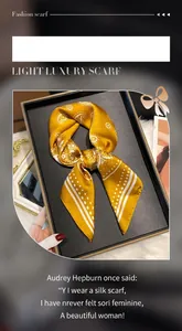 Detailopname van gele zijden sjaal met paisley-patroon in een luxe zwarte geschenkdoos