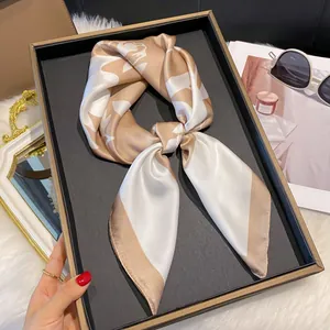 Gros plan d'un carré de soie satiné champagne et blanc présenté dans un coffret cadeau
